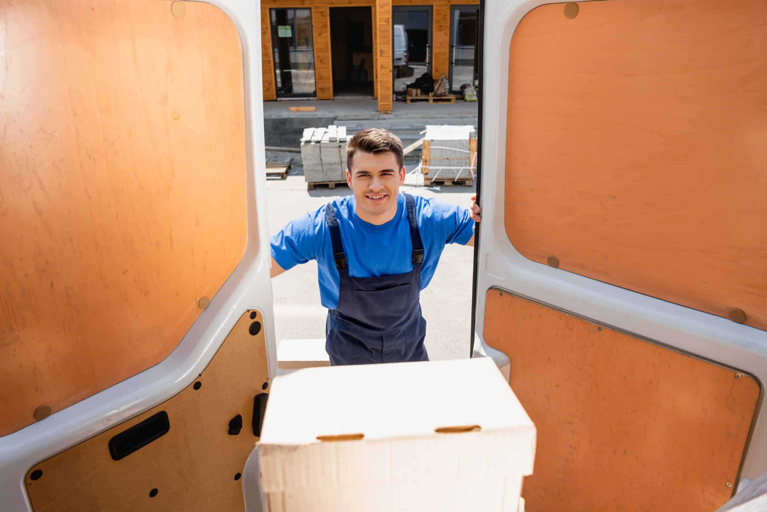 Selective focus of loader looking at camera near package in truck on urban street