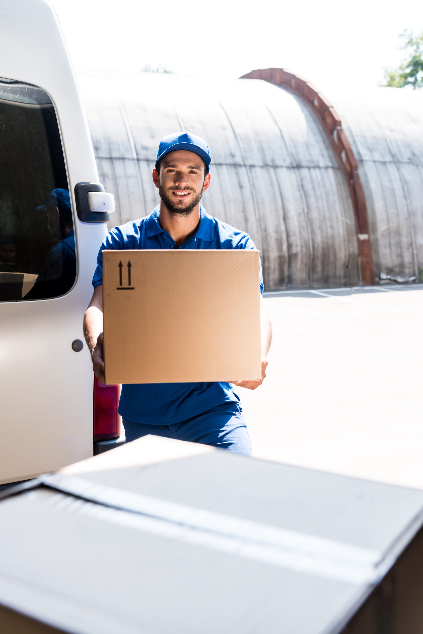 delivery man with cardboard box next to van